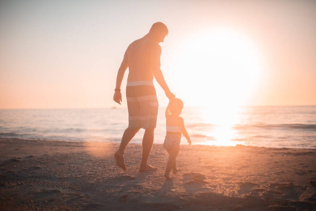 Vater und Kind spazieren am Strand Sinnbild für das Urvertrauen das entstehen kann