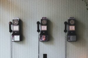 Bedürfnisse kommunizieren per Telefon: Drei altmodische Telefone hängen an der Wand.